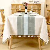 AIMHave modern abstract wave linen look tablecloth featuring fluid blue navy and white geometric shapes with white tassels on a dining table