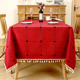 Festive red windowpane plaid linen look tablecloth with white fringe tassels on a wooden dining table