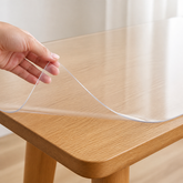 Clear transparent PVC table protector showing the thin smooth edge on a wood tabletop