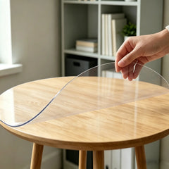 Hand pinching and folding a round transparent mat to show 1.5mm thickness and high flexibility for office use.