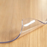 Close-up of PVC table pad showing crystal clear transparency for furniture protection.