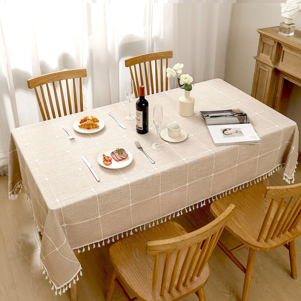 Top view of grey striped poly-cotton blend table cloth with fringe tassels decorated with food and plates