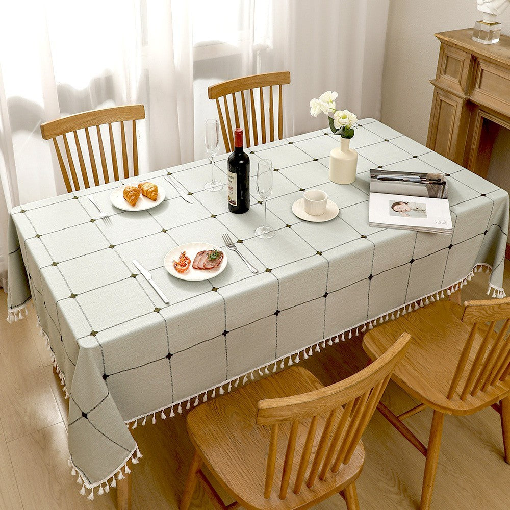 Top view of light green checkered farmhouse poly-cotton tablecloth styled with plates and croissants