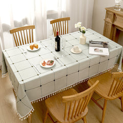 Top view of light green checkered farmhouse poly-cotton tablecloth styled with plates and croissants