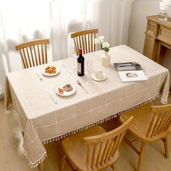 Top view of grey striped poly-cotton blend table cloth with fringe tassels decorated with food and plates