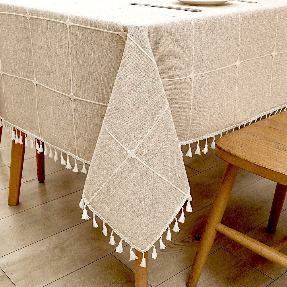 Close-up view of elegant white macrame fringe tassels on an earth-toned coffee striped faux linen tablecloth