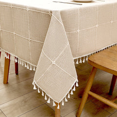 Close-up view of elegant white macrame fringe tassels on an earth-toned coffee striped faux linen tablecloth
