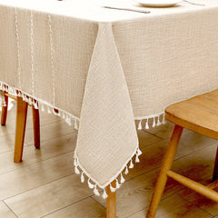 Close-up of elegant white macrame fringe tassels on an AIMHave rich coffee brown oversized grid lattice faux linen tablecloth