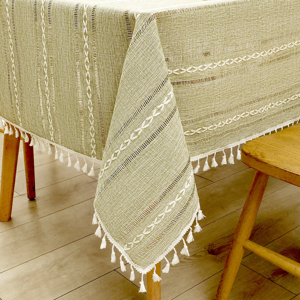 Close-up of elegant white macrame fringe tassels on an AIMHave green and cream striped faux linen tablecloth