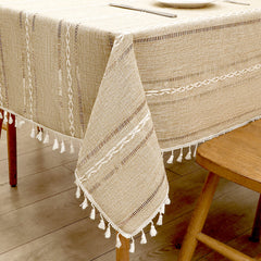 Close-up of elegant white macrame fringe tassels on an AIMHave coffee brown and cream striped faux linen tablecloth