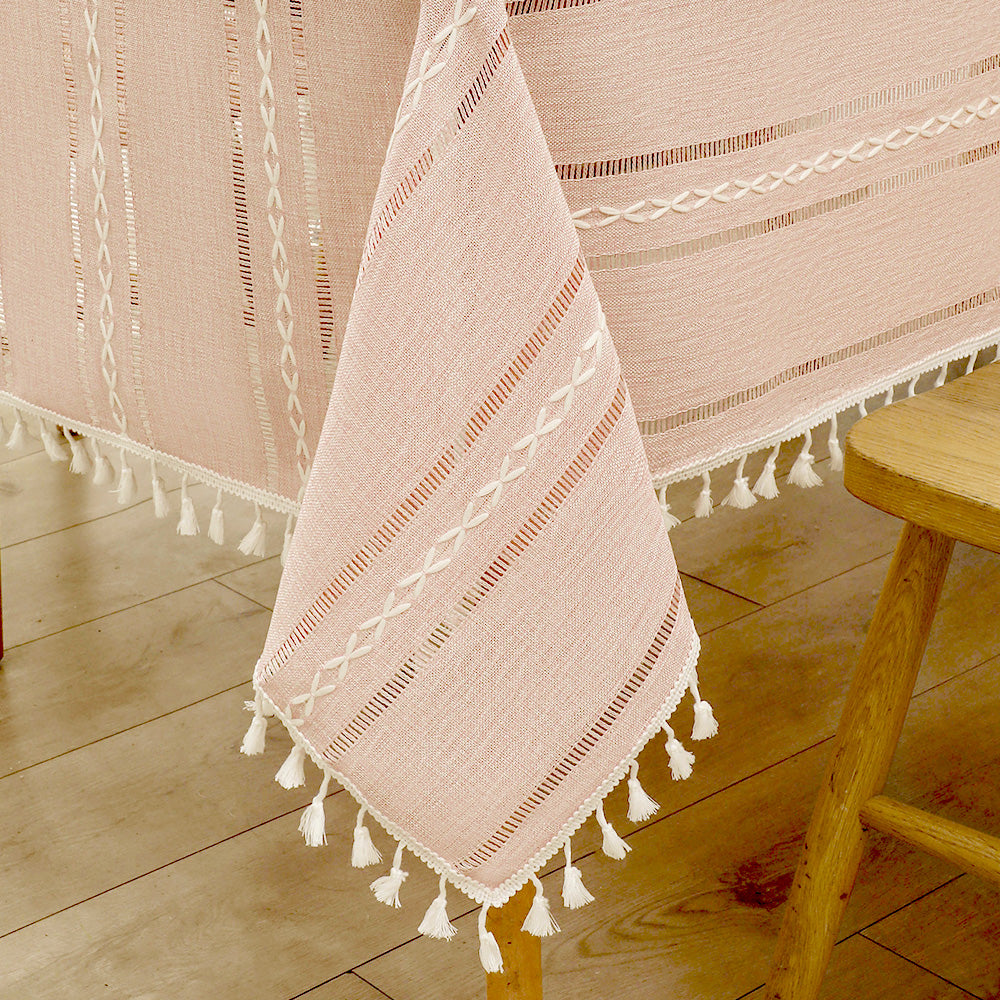Close-up of elegant white macrame fringe tassels on an AIMHave dusty rose pink and cream striped faux linen tablecloth