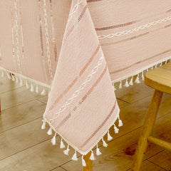Close-up of elegant white macrame fringe tassels on an AIMHave dusty rose pink and cream striped faux linen tablecloth