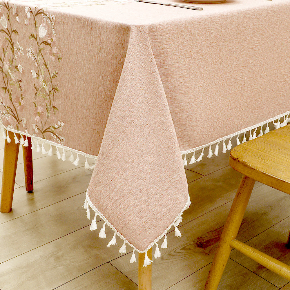 Close-up of elegant white macrame fringe tassels on an AIMHave dusty rose embroidered wildflower pattern tablecloth