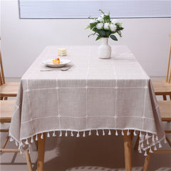 Warm autumn decor dining table styled with a retro coffee plaid tablecloth featuring white tassels and flower vase