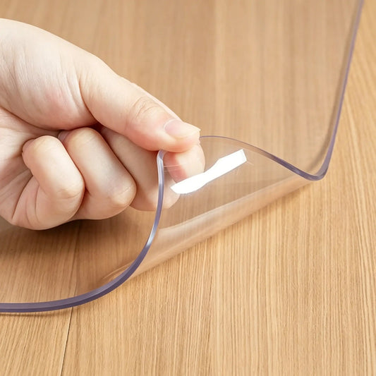 Hand lifting the corner of a 13x16 PVC bedside mat to show 1.5mm thickness and clear, non-slip material.