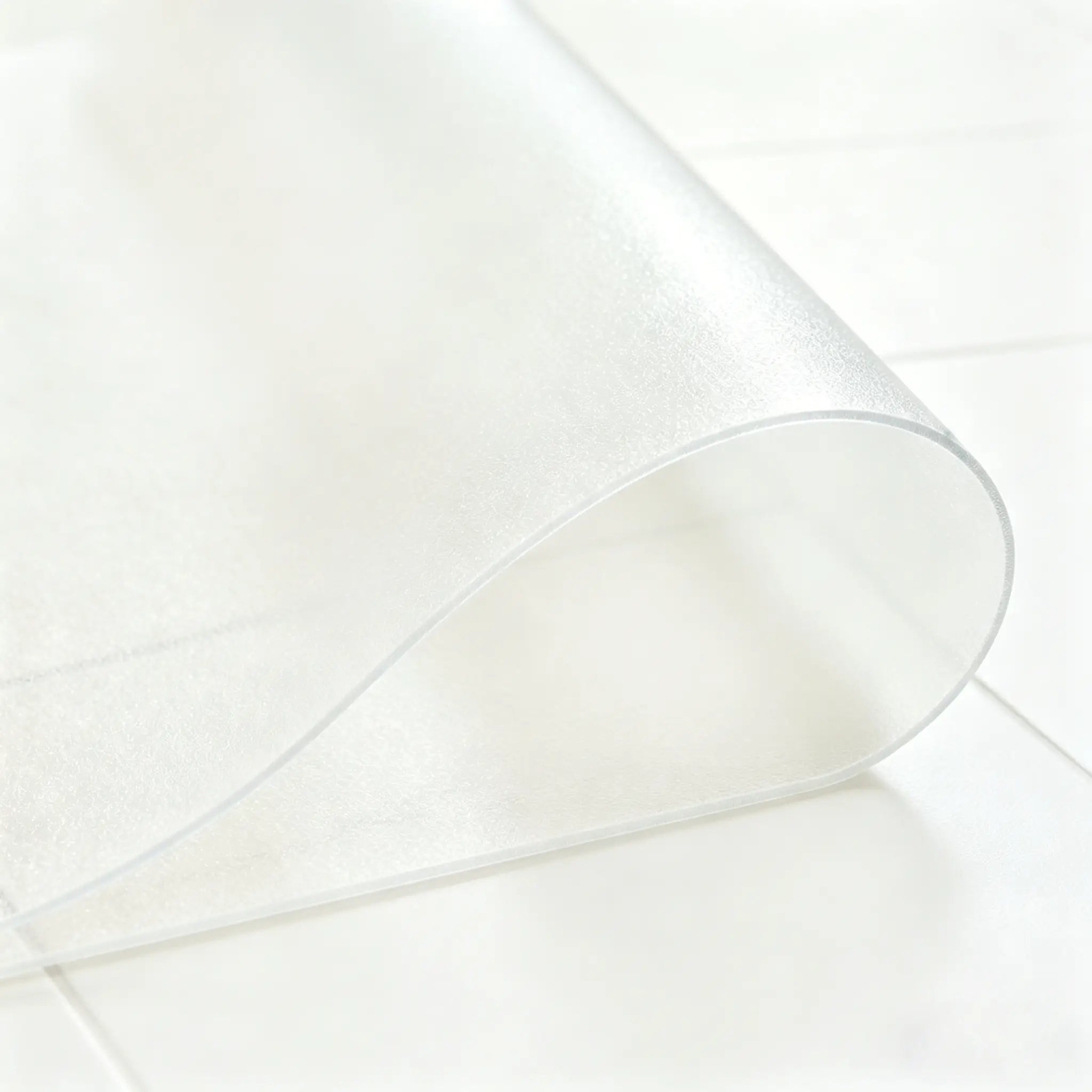 Close-up of frosted PVC bathroom mat being folded in the middle to demonstrate high flexibility and durability.