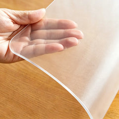 Hand pinching a frosted PVC mat to show 1.5mm thickness and premium flexible material for furniture protection.